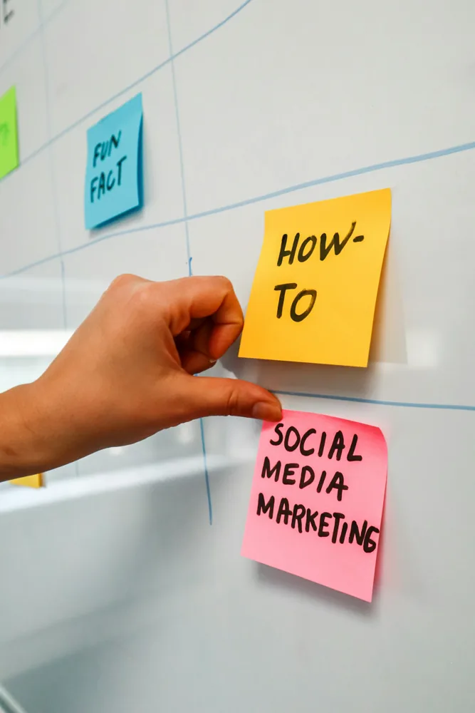 Mão organizando notas de planejamento de marketing de redes sociais.